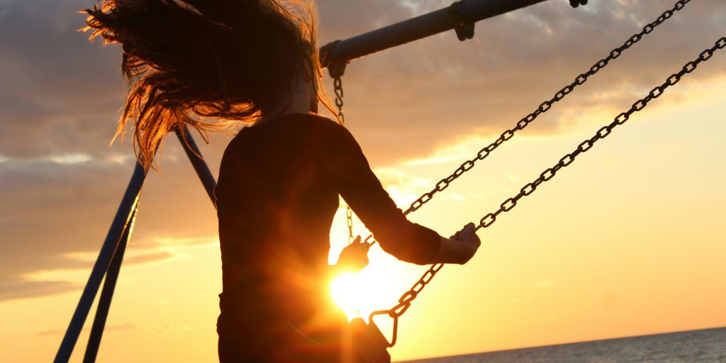 woman riding on swing during sunset