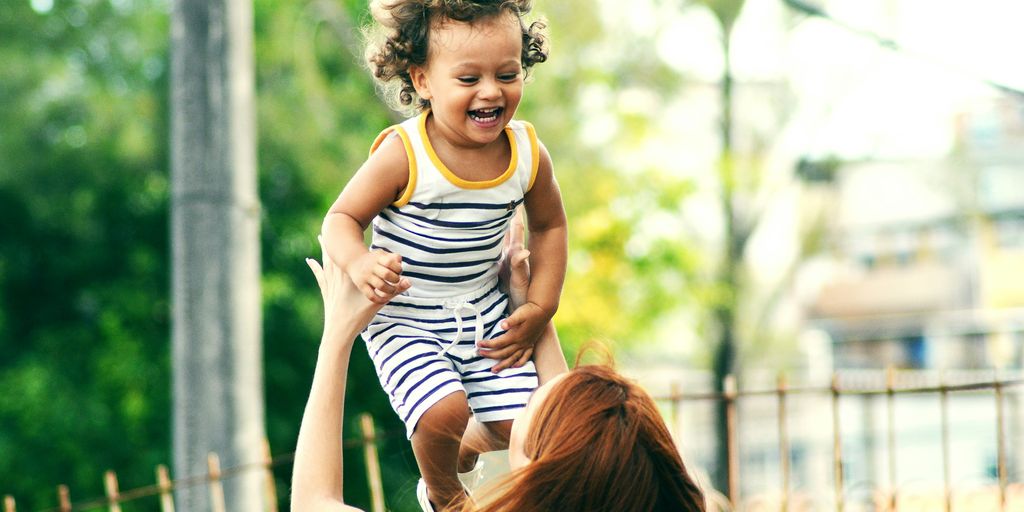 selective focus photo of woman lifting child during daytime