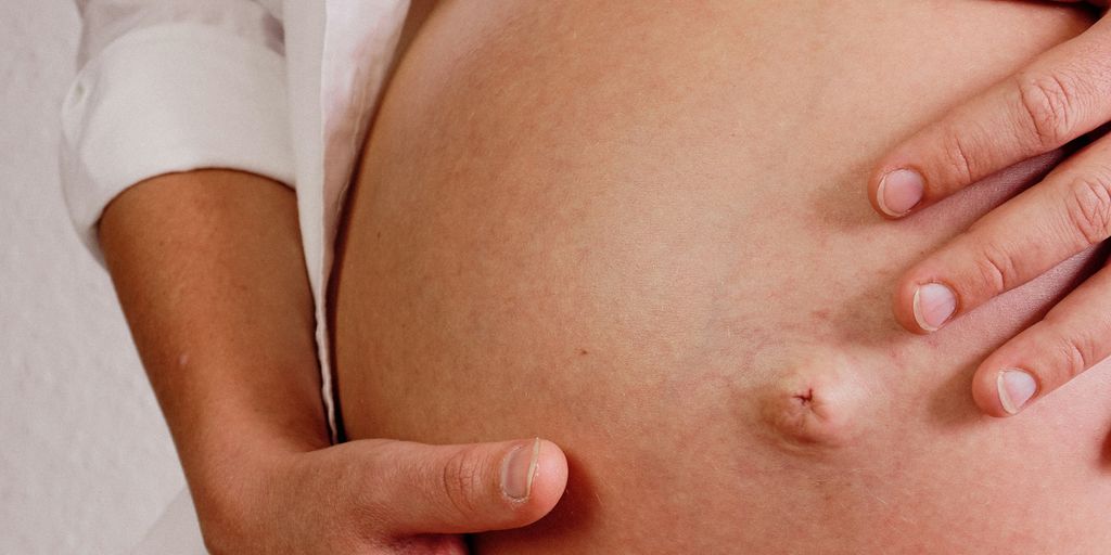 a close up of a person touching a pregnant belly