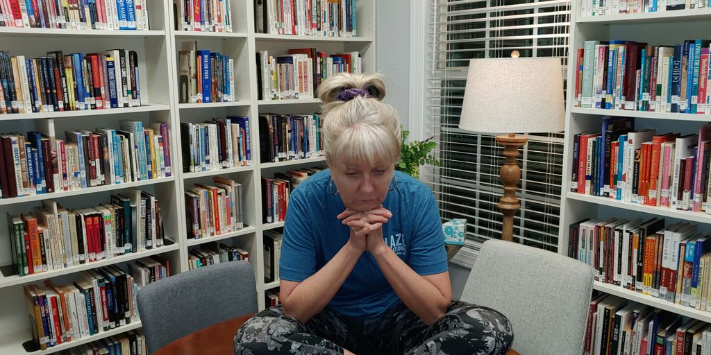 a woman sitting on a table in front of a bookshelf