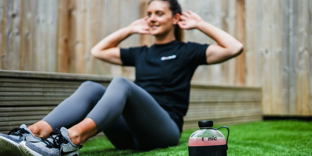 woman in black crew neck t-shirt and black leggings lying on green grass field