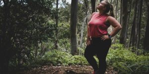 woman in red tank top and black pants standing on forest during daytime