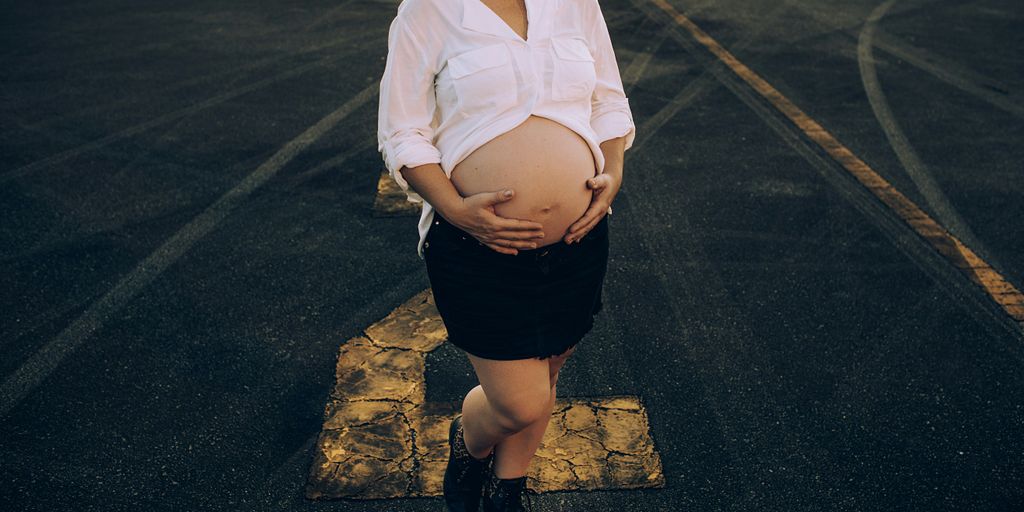 woman in white dress shirt and black skirt standing on gray asphalt road during daytime
