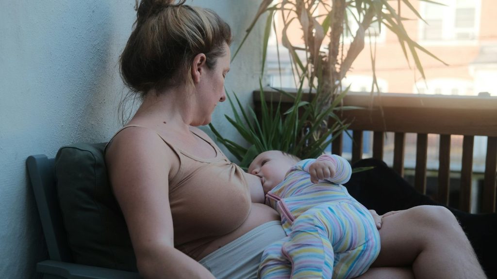 a woman sitting on a bench holding a baby