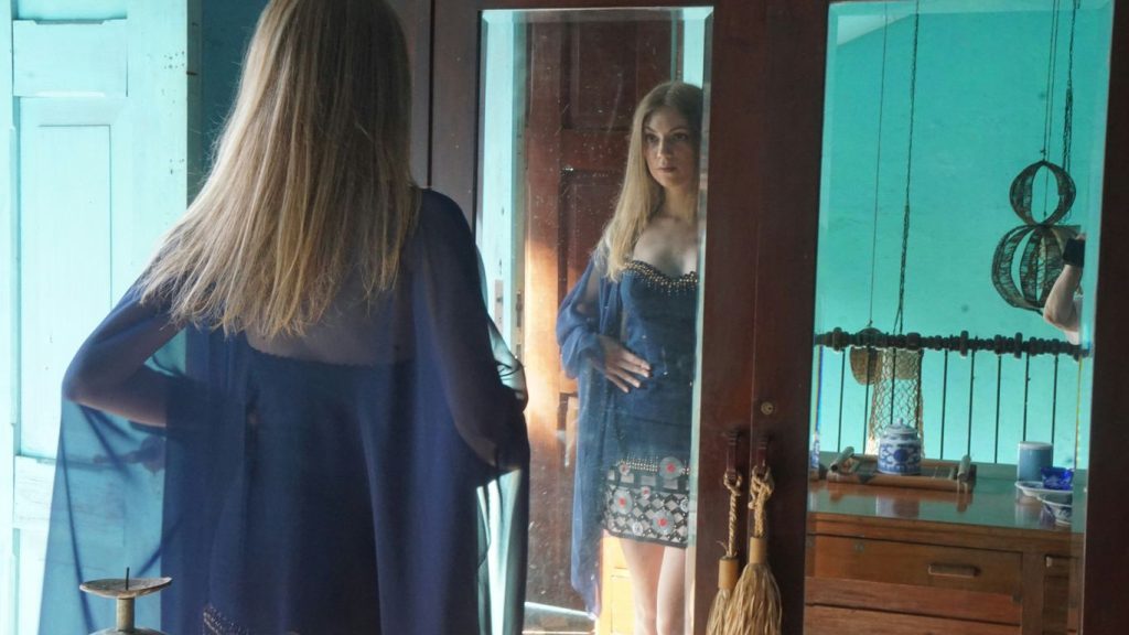 A woman standing in front of a mirror in a room